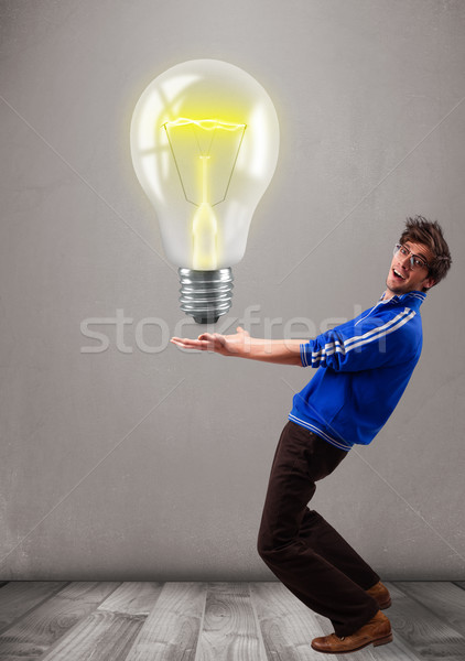 Attractive man holding realistic 3d light bulb Stock photo © ra2studio