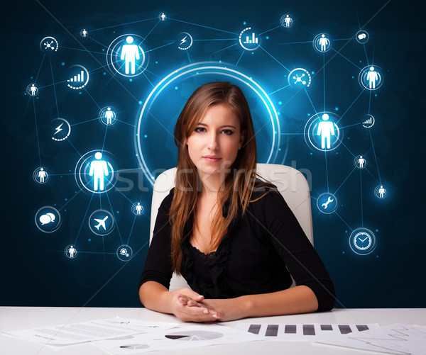 Businesswoman sitting at desk with social network icons Stock photo © ra2studio