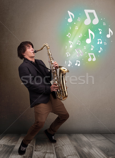 Young musician playing on saxophone while musical notes explodin Stock photo © ra2studio