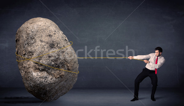 Stock photo: Businessman pulling huge rock with a rope 