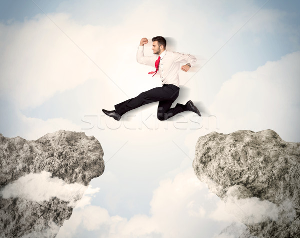 Stock photo: Happy business man jumping over a cliff 