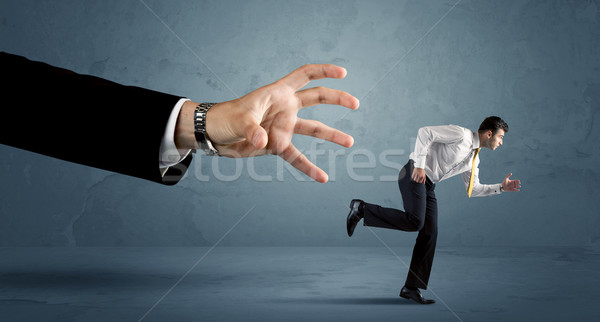 Stock photo: Business man running away from a huge hand concept