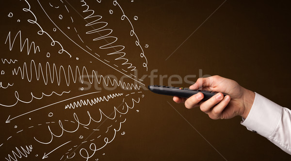 Hand with remote control and curly lines Stock photo © ra2studio