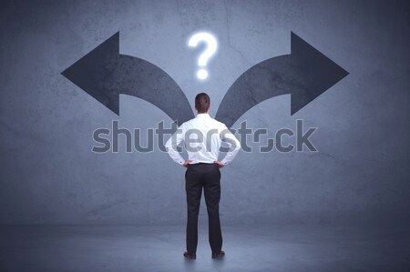 Stock photo: Businessman taking a decision while looking at arrows on the wall concept