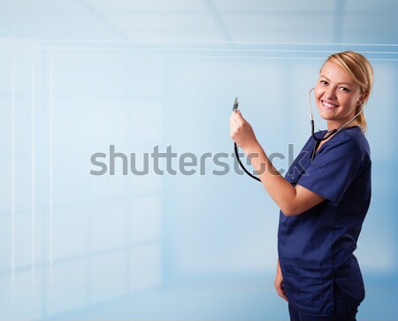 Pretty young nurse in hospital listening to empty copy space with sthetoscope Stock photo © ra2studio