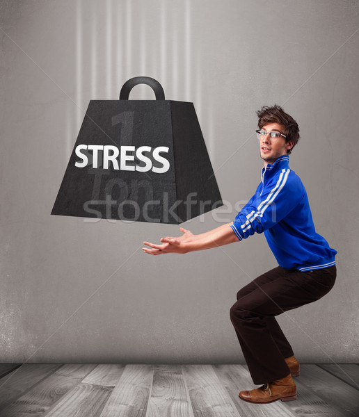 Handsome boy holding one ton of stress weight Stock photo © ra2studio