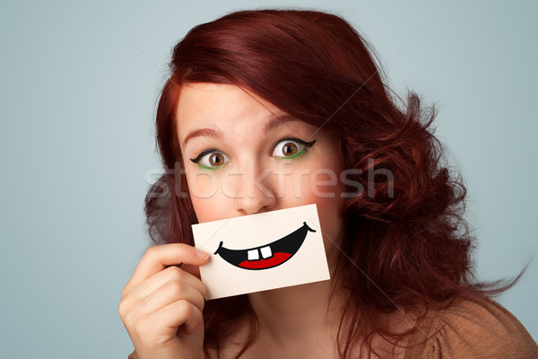 Happy pretty woman holding card with funny smiley Stock photo © ra2studio