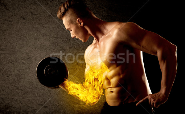Stock photo: Muscular bodybuilder lifting weight with flaming biceps concept