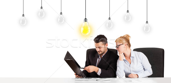 Business man and woman sitting at table with idea light bulbs Stock photo © ra2studio