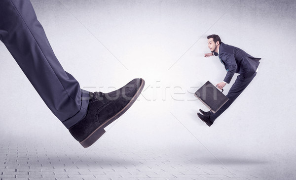 Young worker kicked out by big foot Stock photo © ra2studio