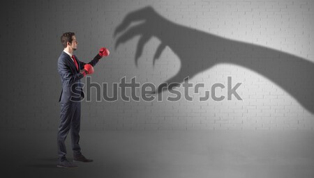 Businessman fighting with scary hand shadow Stock photo © ra2studio
