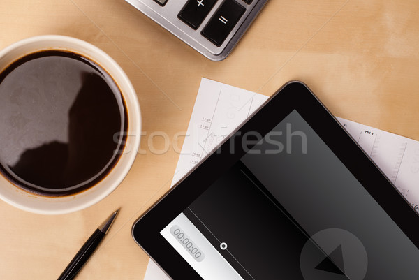 Workplace with tablet pc showing media player and a cup of coffee on a wooden work table closeup Stock photo © ra2studio