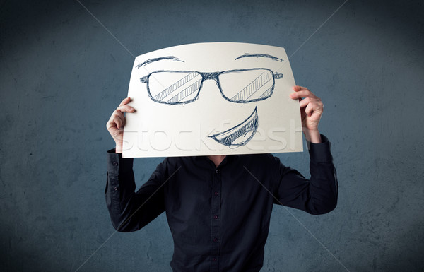 Businessman holding a paper with smiley face in front of his hea Stock photo © ra2studio