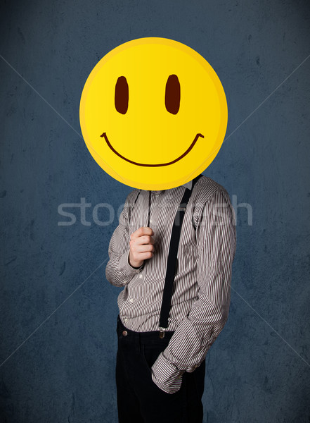 Stock photo: Businessman holding a smiley face emoticon
