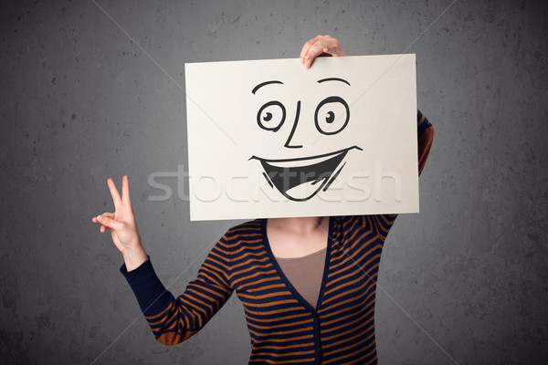 Woman holding a cardboard with smiley face on it in front of her Stock photo © ra2studio