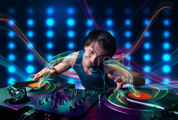 Stock photo: Young Dj mixing records with colorful lights