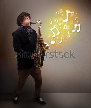 Young musician playing on saxophone while musical notes explodin Stock photo © ra2studio