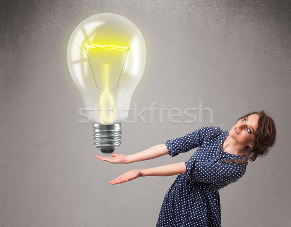 Beautiful lady holding realistic 3d light bulb Stock photo © ra2studio
