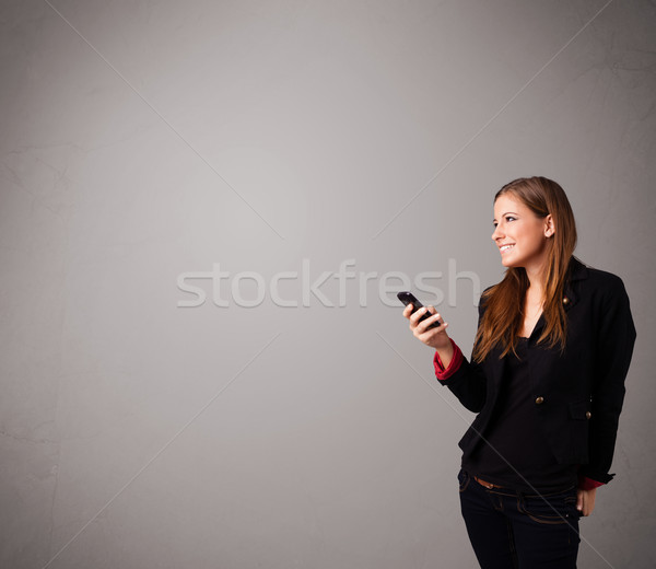 young lady standing and holding a phone with copy space Stock photo © ra2studio