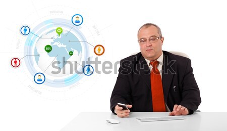 businessman sitting at desk and holding a mobilephone with globe and social icons, isolated on white Stock photo © ra2studio