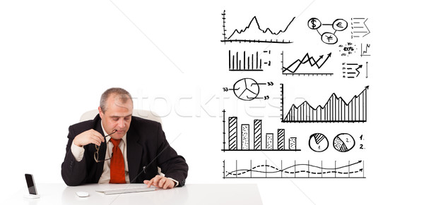 Stock photo: Businessman sitting at desk with diagrams and graphs