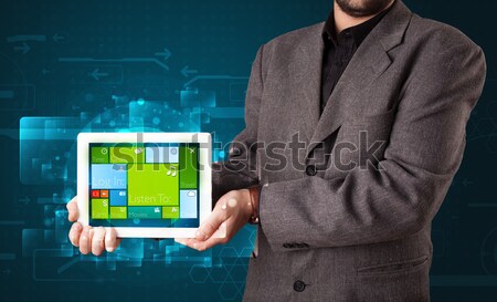 Stock photo: Young businessman holding a tablet with modern software operational system