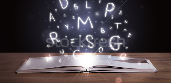Stock photo: Open book with glowing letters flying out