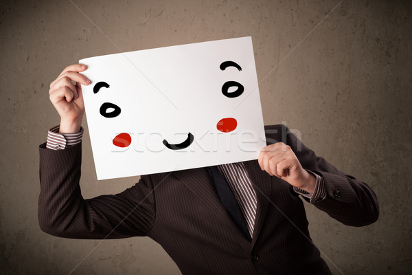 Stock photo: Businessman holding a cardboard with a smiley face on it