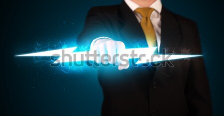 Stock photo: Business man holding glowing lightning bolt in his hands