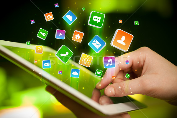 Hand using tablet with application icons flying around Stock photo © ra2studio