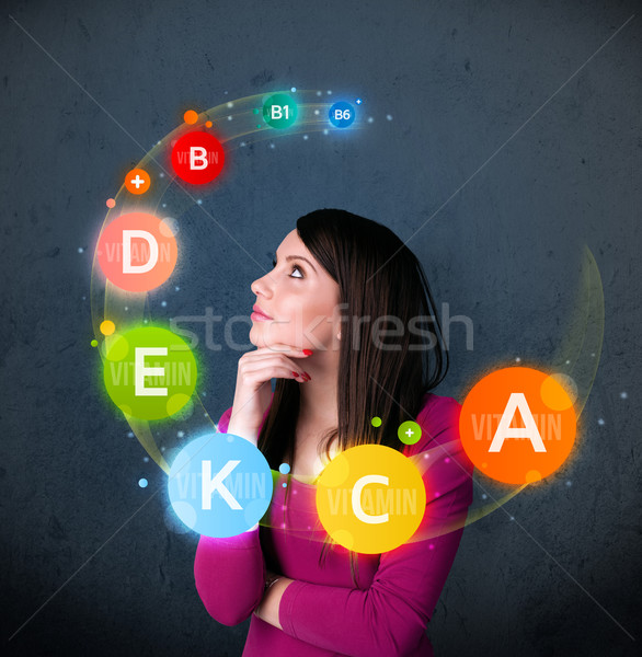 Young woman thinking with vitamins circulation around her head Stock photo © ra2studio