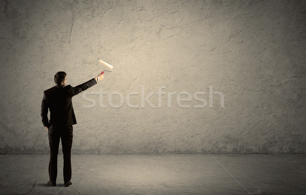 Salesman with roller standing at empty wall Stock photo © ra2studio