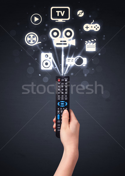Hand with remote control and media icons Stock photo © ra2studio