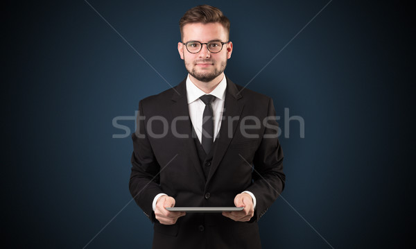 Businessman holding tablet with dark background Stock photo © ra2studio