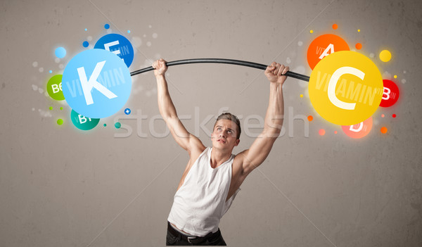 Stock photo: muscular man lifting colorful vitamin weights