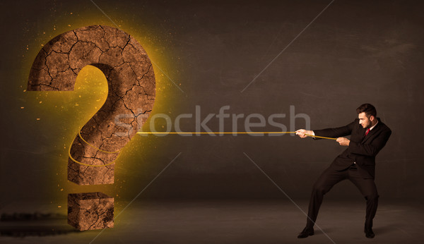 Stock photo: Business man pulling a big solid question mark stone