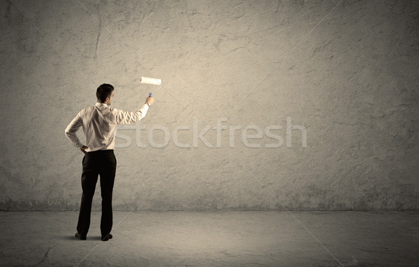 Salesman with roller standing at empty wall Stock photo © ra2studio