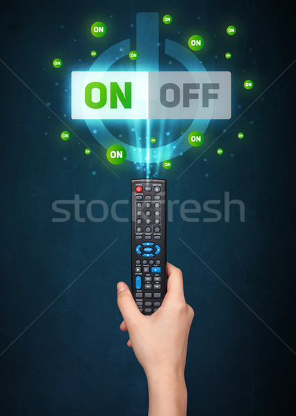 Hand with remote control and on-off signals Stock photo © ra2studio