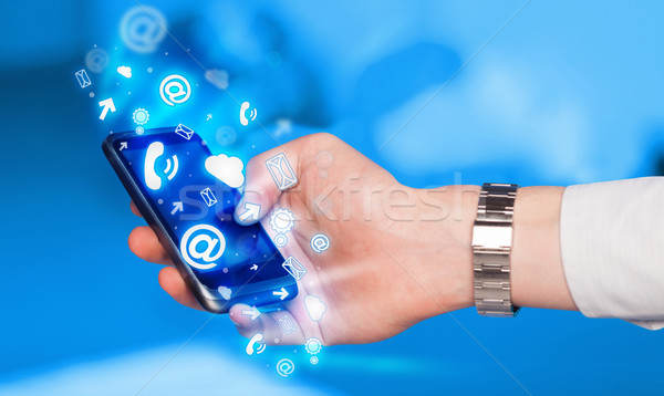 Business man holding smart phone with media icons Stock photo © ra2studio