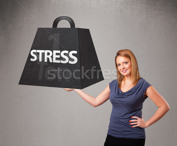 Young woman holding one ton of stress weight Stock photo © ra2studio
