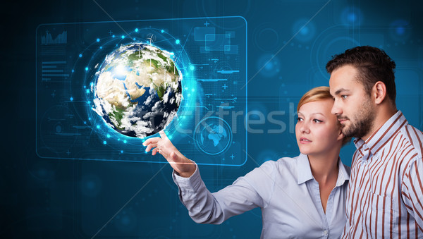 Young couple touching high-tech 3d earth panel Stock photo © ra2studio