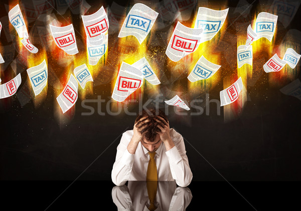 Depressed businessman sitting under burning tax and bill papers Stock photo © ra2studio
