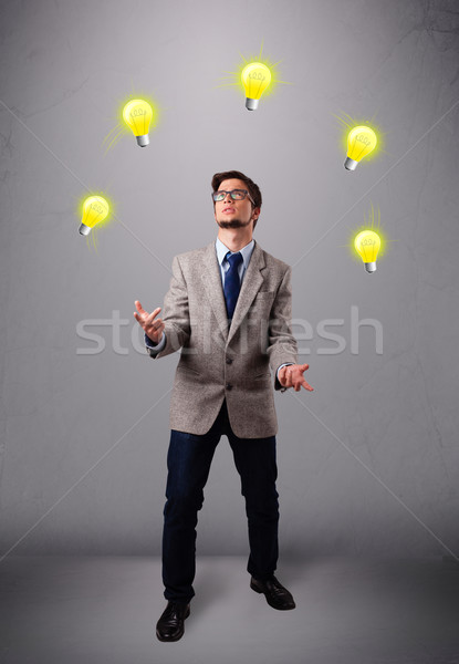 young man standing and juggling with light bulbs Stock photo © ra2studio