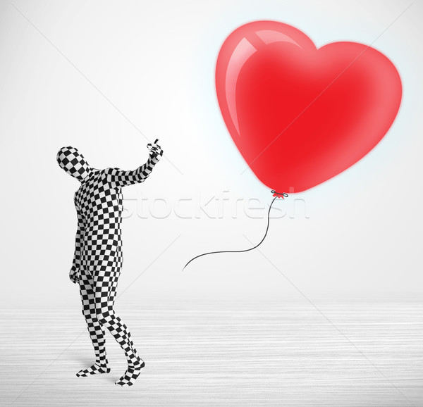 Cute guy in morpsuit body suit looking at a red balloon shaped heart Stock photo © ra2studio