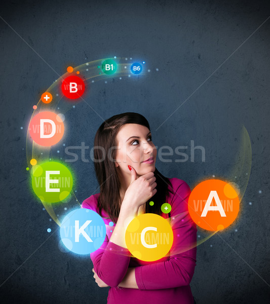 Young woman thinking with vitamins circulation around her head Stock photo © ra2studio