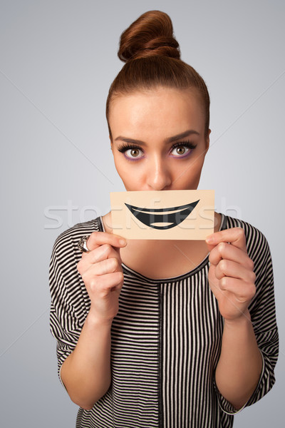 Happy pretty woman holding card with funny smiley Stock photo © ra2studio