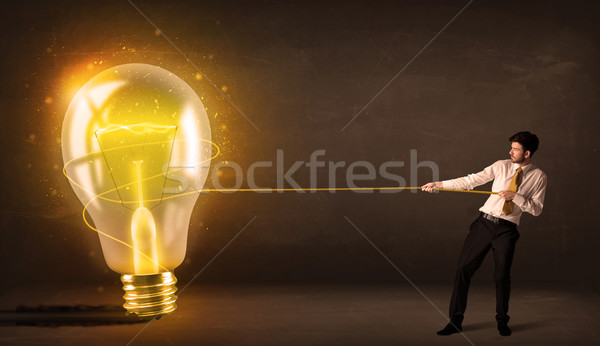 Stock photo: Business man pulling a big bright glowing light bulb