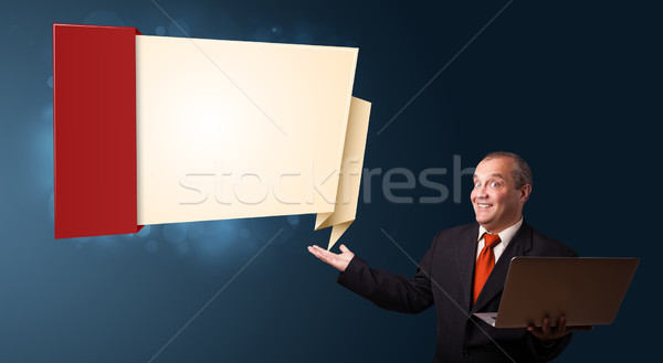 Businessman in suit holding a laptop and presenting modern origami copy space Stock photo © ra2studio