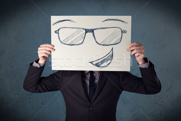 Stock photo: Businessman holding a paper with smiley face in front of his hea