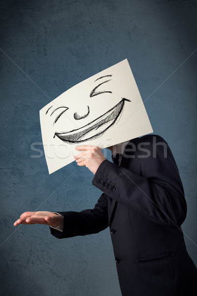 Stock photo: Businessman holding a paper with smiley face in front of his hea